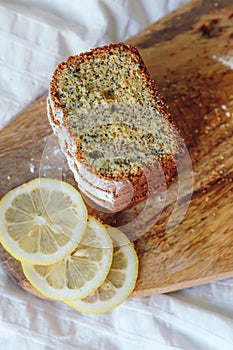 Cake with poppy seeds and lemon zest, sprinkled with powdered sugar. Cupcake with lemon on a wooden board.