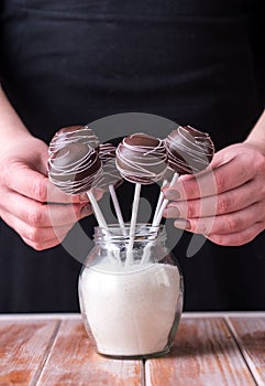 Cake pops in chocolate cream in the form of a bouquet stand in jars with sugar on a wooden background