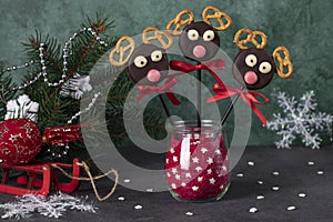 Cake pops Santa reindeers made from cookies in chocolate and crackers on green, Idea Christmas treats for childrens