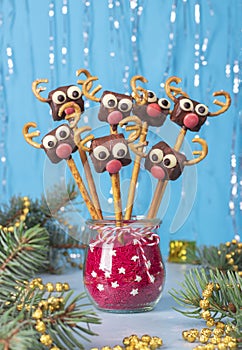 Cake pops Santa reindeers from marshmallows, sweet straw and chocolate on blue, Idea Christmas treats for kids