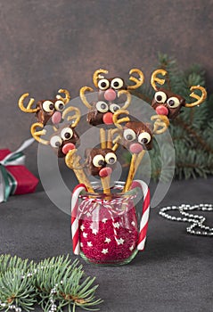 Cake pops Santa reindeers from marshmallows, sweet straw and chocolate on brown background, Idea Christmas treats for