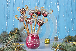 Cake pops Santa reindeers from marshmallows, sweet straw and chocolate on blue background, Idea Christmas treats for