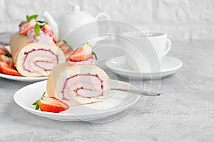 Cake roll with fresh strawberries, jam and cream cheese on a white plate on a gray background. Copy space