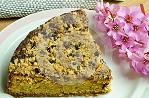 Cake slice with pieces of hazelnuts and chocolate, on the right a pink flower