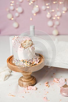 Cake smash scene - little white bed with pink baby shoes, cake left overs
