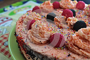 Cake with strawberries, blackberries and colorful sprinkles on the green plate and colorful strawberry