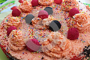 Cake with strawberries, blackberries and colorful sprinkles on the green plate and colorful strawberry