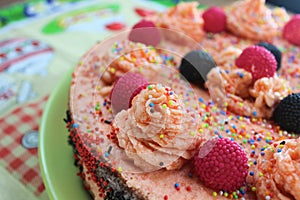 Cake with strawberries, blackberries and colorful sprinkles on the green plate and colorful strawberry