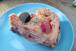 Cake with strawberries, blackberries and colorful sprinkles on the green plate and colorful strawberry