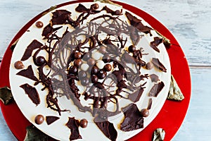 Cake with three types of chocolate, garnished with chocolate shavings on a red plate