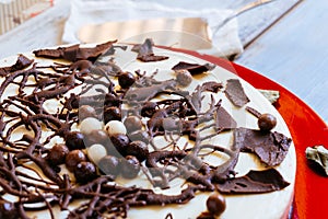 Cake with three types of chocolate, garnished with chocolate shavings on a red plate