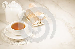 Cake a tubule with white cream and tea cup/cake a tubule with white cream and tea cup on a white marble background. Copy space