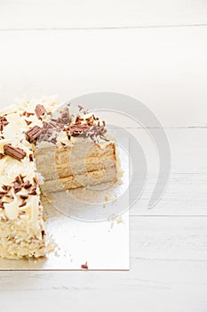 Cake vertical. Delicious layered cake with vanilla frosting with white and milk chocolate flakes sprinkled on top