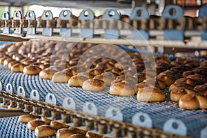 Cakes on automated round conveyor machine in bakery food factory, production line photo
