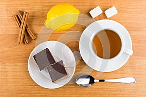 Cakes with chocolate in saucer, cinnamon sticks, lemon, sugar, t