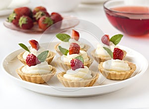 Cakes, cupcakes with fresh fruits (strawberries), whipped cream and mints
