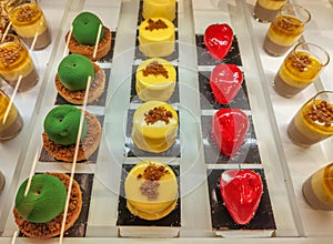 Cakes and mouses of various colors, green, yellow, red, brown including puff pastry, pastry cream