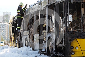 Cal Fire firefighter climbs a ladder by burnt traffic bus