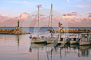 Cala Bona Port, fishing boats with reflections, cloudy sky and moon, Mallorca, Spain