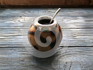 Calabash and mate bombilla on wooden background