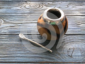 Calabash and mate bombilla on wooden background