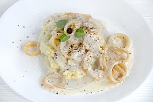 Calamary rings potato sauce white plate