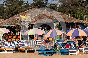 Caucasian tourists relaxing on the beach beds of a restaurant shack on a beach in Goa