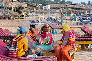 Women wearing colorful clothes sitting on a beach bed and having a cheerful conversation at