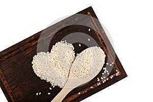 Calasparra rice or arroz calasparra in heart shape on brown wooden cutting board and spoon. Spanish processed white bomba rice