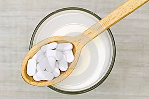 Calcium carbonate tablets above a glass of fresh milk