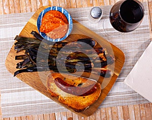 Calcot served on table with romesco sauce and botifarra