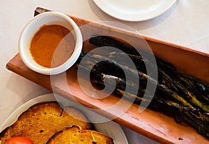 Calcots onions served on plate with Romesco sauce - traditional Catalan dish