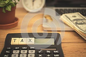 Calculating and paying TAX concept background. Business desktop with calculator, laptop and dollar bills. Business photo