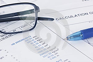 Calculation document with pen and eyeglasses