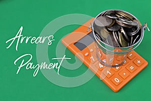 Calculator and coins over green background written with ARREARS PAYMENT