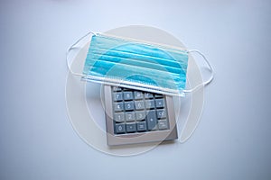 Calculator and face mask pandemic disease covid19 coronavirus global financial crisis concept photo