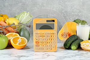 Calculator and food products on white marble table. Weight loss concept