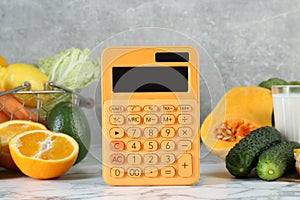 Calculator and food products on white marble table. Weight loss concept