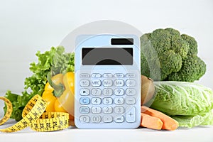 Calculator and food products on white wooden table. Weight loss concept