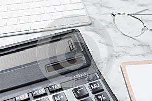 Calculator, keyboard and glasses on white marble table, closeup. Tax accounting