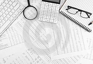 Calculator, keyboard, magnifying glass, pen, eye glasses lying on financial documents . Financial and business concept. Top view