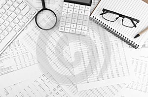 Calculator, keyboard, magnifying glass, pen, eye glasses lying on financial documents . Financial and business concept. Top view