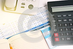 A calculator, a landline phone with buttons, a diary and financial documents on the desktop. Business concept and