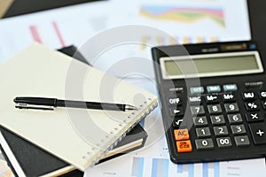 Calculator machine, notepad and financial documents on office table