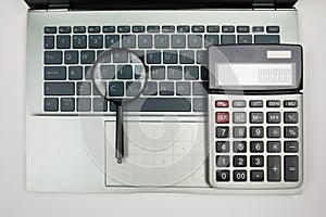 calculator and magnifying glass on laptop keyboard