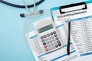 Calculator on medical billing statement with pen on blue background