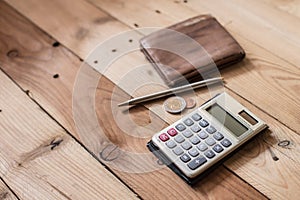 Calculator with money pocket on wood background
