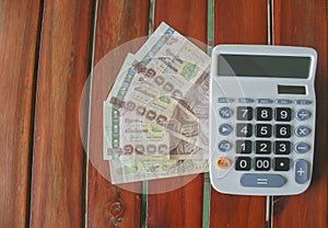 Calculator and money thai banknote on wooden table at home office. The concept of financial planning, savings