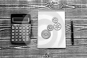 Calculator, notebook, gears on a wooden background. business planning.