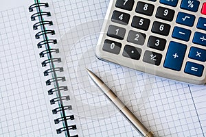 Calculator and notebook with pen on desktop